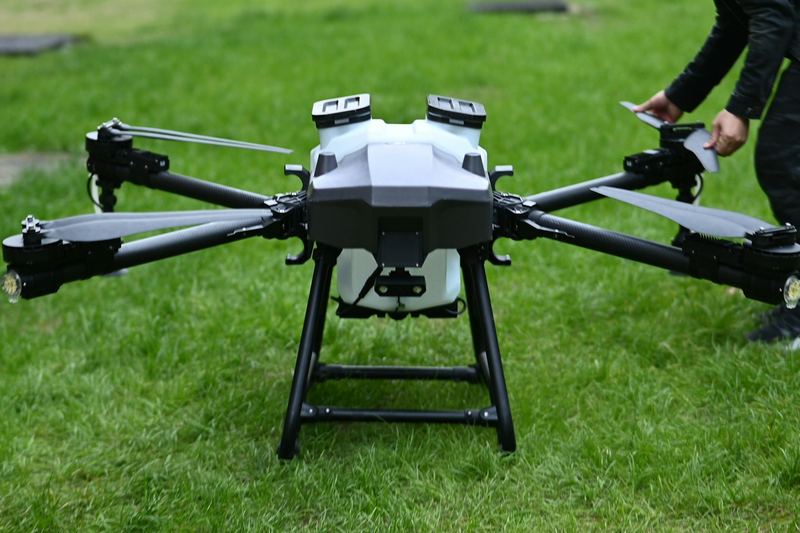 Dron penyembur pertanian dengan lengan terbuka di atas rumput sebelum berlepas